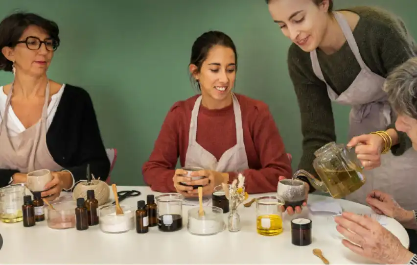 4 dames souriantes fabriquent des cosmétiques naturels. L'animatrice sert du thé.
