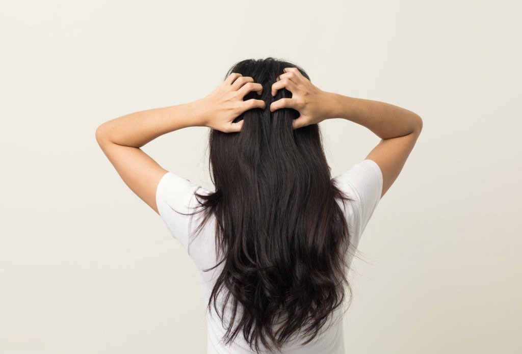 Femme brune vu de dos qui se gratte les cheveux