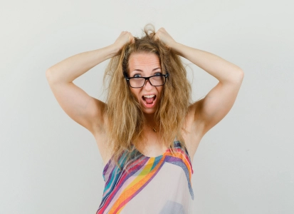 Jeune femme blonde énervée s'arrachant les cheveux.
