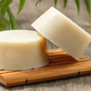 rondelle de shampoing solide naturel beige sur porte savon en bois